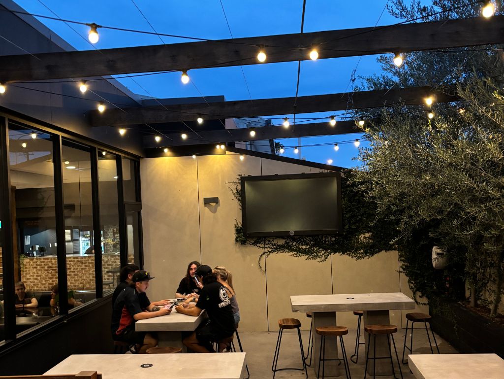 Tall olive trees and festoon lighting set the scene in Hops & Vine bar Emerald's outdoor courtyard